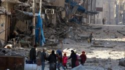 Syrians walking in rubble, trying to leave Aleppo warzone