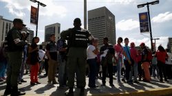 Venezuelan National Guard members control the crowd as people queue to deposit their 100 bolivar notes, near Venezuela's Central Bank in Caracas, Venezuela