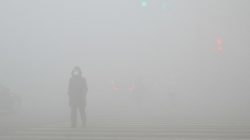 People walk past a street in heavy smog during a polluted day in Weifang, Shandong province,