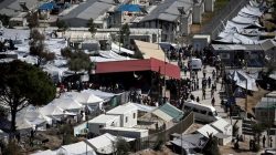 Refugees and migrants line up for food distribution at the Moria migrant camp