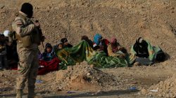Iraqi soldier standing guard over civilians who fled Mosul and Islamic State