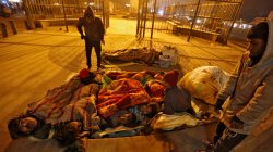 A family gather under blankets to shelter from the cold beneath a flyover in Delhi, India
