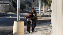 Young boy in the Andalus district holds up his shirt to show Iraqi forces that he is not wearing a suicide vest during an operation to clear the al-