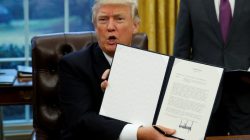 President Donald Trump holds up executive order