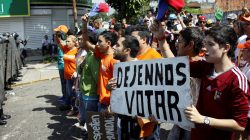 Protesters in Venezuela hold sign that reads "Let us vote"