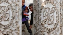 Iraqi children stand behind the doors of their home during a fight with Islamic State militants in Rashidiya, North of Mosul, Iraq, January 30,2017.