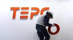 A worker puts up new logo of TEPCO Holdings and Tokyo Electric Power Company (TEPCO) Group on the wall ahead of the transition to a holding company system through a compan