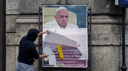 A worker covers with a banner reading "illegal poster" a poster depicting Pope Francis and accusing him of attacking conservative Catholics, in Rome, Italy,
