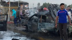People and Iraq forces gather around car bombing sight