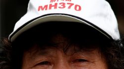 A family member of a passenger aboard Malaysia Airlines flight MH370 which went missing in 2014 reacts during a protest outside the Chinese foreign ministry in Beijing, July 29, 2016. The hat reads "Pray for MH370" REUTERS/Thomas Peter