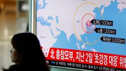 A woman walks past a television broadcasting a news report on North Korea firing ballistic missiles, at a railway station in Seoul, South Korea,