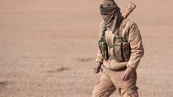 An Syrian Democratic Forces (SDF) fighter walks with his weapon in northern Raqqa province, Syria