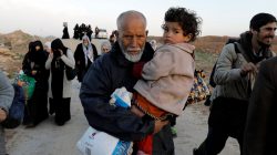 A displaced Iraqi man carries his granddaughter while fleeing his home, as Iraqi forces battle with Islamic State militants, in western Mosul, Iraq March 8, 2017. REUTERS/Zohra Bensemra