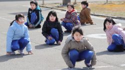 Elementary school students squat down on the street as they participate in an evacuation drill for local residents based on the scenario that a ballistic missile launched landed in Japanese waters, in Oga, Akita prefecture, Japan March 17, 2017. Kyodo/via REUTERS