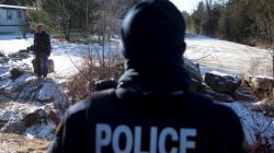A man is confronted by a Royal Canadian Mounted Police officer as he prepares to cross the U.S.-Canada border leading into Hemmingford, Quebec.