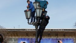 A law enforcement officer climbs on a lamp pole to detain opposition supporters during a rally in Moscow. REUTERS/Sergei