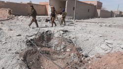Syrian Democratic Forces (SDF) fighters walk near damaged ground east of Raqqa city, Syria.