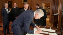 Chief Justice of the United States John Roberts (C) looks on as Judge Neil Gorsuch (R) signs the constitutional oath during swearing-in ceremony at the Supreme Court in Washington, U.S.