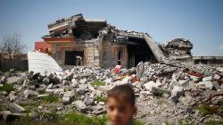 An Iraqi boy walks past a building destroyed during the fighting between Iraqi forces and Islamic states militants in Qayyara,