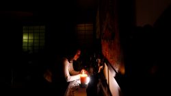 Maha Ragaay prays and lights a candle in front of a wooden figure of Jesus on a cross in her home at the Cairo suburb of Maadi, Egypt, April 14, 2017. REUTERS/Amr Abdallah Dalsh