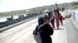An Iraqi woman carries a girl as she walks along a pontoon bridge over the Tigris river on the outskirts of Hammam al-Alil, south of Mosul, Iraq, April 17, 2017. REUTERS/Andres Martinez Casares