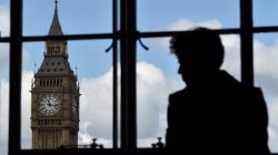 A woman looks out of a window at the Big Ben clock tower in London, Britain,