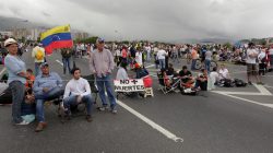 Opposition supporters sit next to a placard that reads: "No more deaths", as they block a highway, during a protest against Venezuelan President Nicolas Maduro's government in Caracas, Venezuela May 15, 2017. REUTERS/Christian Veron