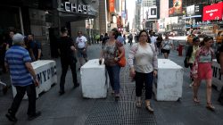 People walk between newly erected concrete barricades outside the 3 Times Square building in Times Square where a speeding vehicle struck pedestrians Thursday in New York City, U.S., May 19, 2017. REUTERS/Mike Segar