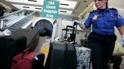 A TSA worker loads suitcases at the checked luggage security screening station at Los Angeles International Airport in Los Angeles, California,