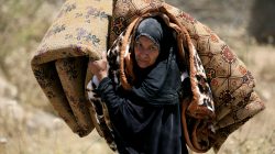 A displaced Iraqi woman who fled her home, carries a mattress in al-Zanjili neighbourhood, north of Old City district of Mosul, Iraq.