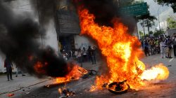 Demonstrators look on as motorcycles belonging to riot security forces are set on fire during a rally against Venezuela's President Nicolas Maduro in Caracas, Venezuela. REUTERS/Carlos Garcia Rawlins
