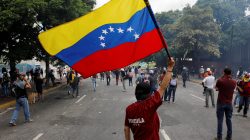 A demonstrator waves a Venezuela's flag while clashing with riot security forces during a rally against Venezuela's President Nicolas Maduro in Caracas, Venezuela June 5, 2017. REUTERS/Carlos Garcia Rawlins