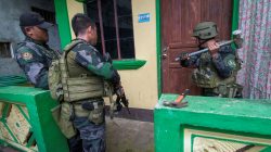 A joint group of police and military forces use a mallet to open a door while conducting a house to house search as part of clearing operations in different sections of Marawi city. REUTERS/Stringer