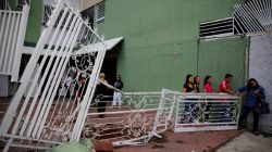 People walk past the broken fencing of a building after opposition supporters and security forces clashed in and outside the building on Tuesday according to residents, in Caracas, Venezuela June 14, 2017. REUTERS/Ivan Alvarado