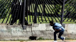 A member of the riot security forces points a gun through the fence of an air force base at David Jose Vallenilla, who was fatally injured during clashes at a rally against Venezuelan President Nicolas Maduro's government in Caracas, Venezuela, June 22, 2017. REUTERS/Carlos Garcia Rawlins/File photo