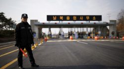 A South Korean security guard stands guard on an empty road which leads to the Kaesong Industrial Complex (KIC) at the South's CIQ (Customs, Immigration and Quarantine), just south of the demilitarised zone separating the two Koreas, in Paju, South Korea, February 11, 2016. The Korean characters on the gateway reads "Inter-Korean Transit Office".