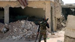 A Free Syrian Army fighter carries weapons as he walks past damaged buildings in a rebel-held part of the southern city of Deraa, Syria July 9, 2017. REUTERS/Alaa Al-Faqir