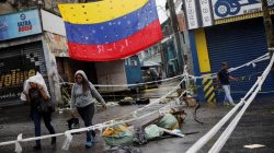 Pedestrians walk past a barricade during a rally against Venezuelan President Nicolas Maduro's government in Caracas, Venezuela, July 19, 2017. REUTERS/Carlos Garcia Rawlins