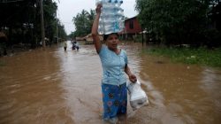 A woman carries water bottles and foods distributed by an aid organization during a flood in Kyaikto township, Mon state, Myanmar July 22, 2017.
