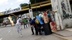 Demonstrators clash with riot security forces while rallying against Venezuela's President Nicolas Maduro's government in Caracas, Venezuela. The banner on the bridge reads "It will be worth it" . REUTERS/Ueslei Marcelino
