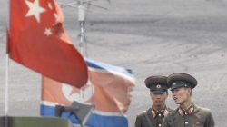 FILE PHOTO: North Korean soldiers chat as they stand guard behind national flags of China (front) and North Korea on a boat anchored along the banks of Yalu River, near the North Korean town of Sinuiju, opposite the Chinese border city of Dandong, June 10, 2013. REUTERS/Jacky Chen