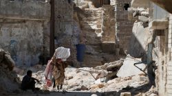 A woman walks on debris of damaged buildings in Aleppo's Sheikh Maqsoud neighbourhood, Syria July 15, 2017. Picture taken July 15, 2017. REUTERS/Omar Sanadiki