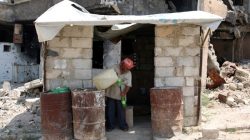A man prepares fuel for sale near damaged buildings in the rebel-held area in Deraa, Syria July 27, 2017. REUTERS/Alaa al-Faqir