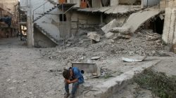 A boy sits near rubble of damaged buildings in Arbin, a town in the Damascus countryside, Syria. REUTERS/Bassam Khabieh