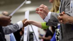 FILE PHOTO: Corporate recruiters (R) gesture and shake hands as they talk with job seekers in Washington, June 11, 2013. REUTERS/Jonathan Ernst/File Photo