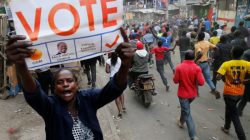 A supporter of Kenyan opposition leader Raila Odinga carries a banner and shouts slogans as others run along a street in Humura neighbourhood, in Nairobi, Kenya August 10, 2017. REUTERS/Thomas Mukoya