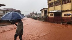 A man walks under umbrella in water covered street in Freetown, Sierra Leone August 14, 2017 in this picture obtained from social media.