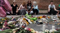 Women sit by an impromptu memorial of flowers commemorating the victims at the scene of the car attack on a group of counter-protesters during the "Unite the Right" rally as people continue to react to the weekend violence in Charlottesville, Virginia. REUTERS/Justin Ide