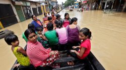 People use a boat as they try to move to safer places along a flooded street in West Midnapore district, in West Bengal