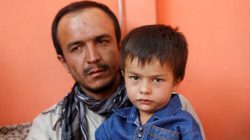 Ali Ahmad, 4, sits with his father as they pose for a photograph at their house after he survived a suicide attack at a mosque in Kabul, Afghanistan August 27, 2017.